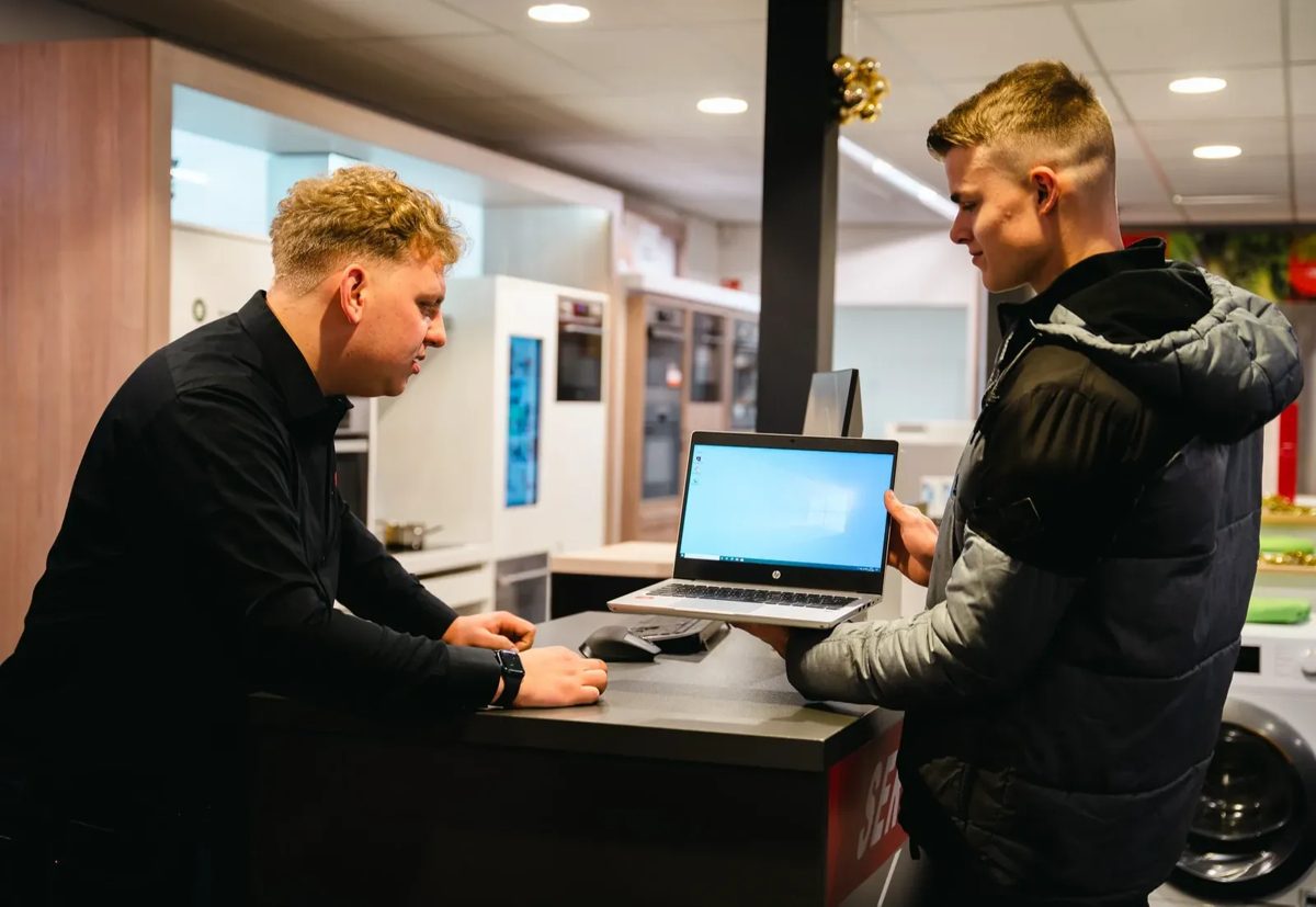 Een medewerker van Vobis laat een klant een laptop zien